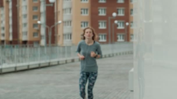 Mulher fitness muito sorridente usando aplicativo em execução antes da corrida para acompanhar o ritmo em smartwatch, feliz sorridente mensagem de mensagens de texto menina esportiva no smartphone antes do treino matinal — Vídeo de Stock