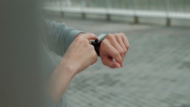 Szép mosolygó fitness nő segítségével a Futtatás előtt futó app pályán üteme smartwatch, boldog, mosolygós sportos lány SMS üzenet-ra smartphone reggel edzés előtt — Stock videók