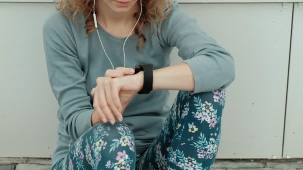 Szép mosolygó fitness nő segítségével a Futtatás előtt futó app pályán üteme smartwatch, boldog, mosolygós sportos lány SMS üzenet-ra smartphone reggel edzés előtt — Stock videók
