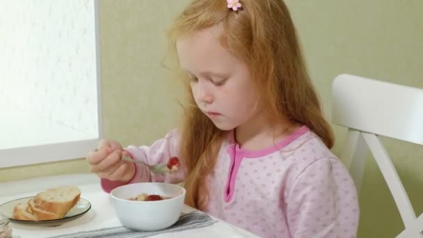 Niña comiendo gachas en la cocina en casa — Vídeo de stock