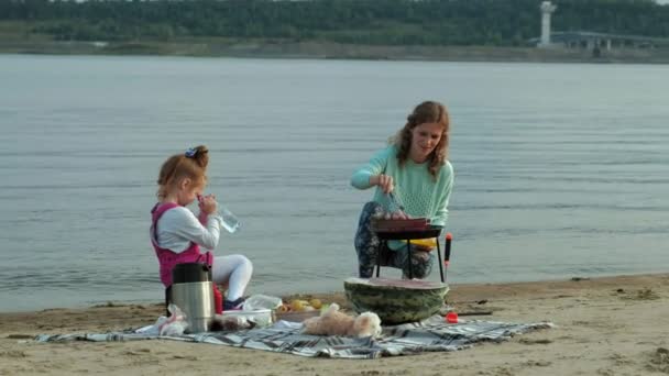 Matka a dcera osmažíme maso a zelenina na grilu na pláži na pláži — Stock video