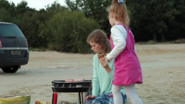 Мать и дочь жарят мясо и овощи на барбекю на пляже на пляже — стоковое видео