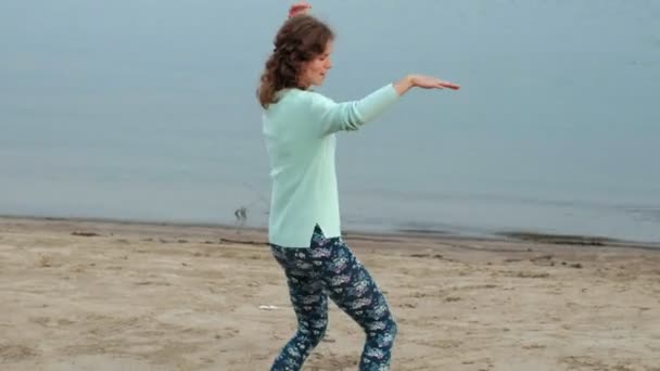 Feliz madre e hija bailando y saltando frente al océano salvaje en otoño — Vídeo de stock