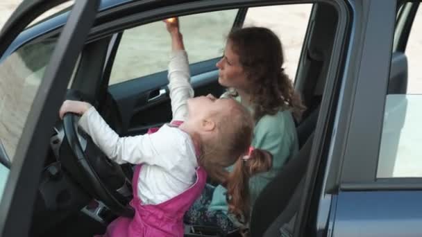 Щаслива мати і дочка танцюють і стрибають перед диким океаном восени біля машини — стокове відео