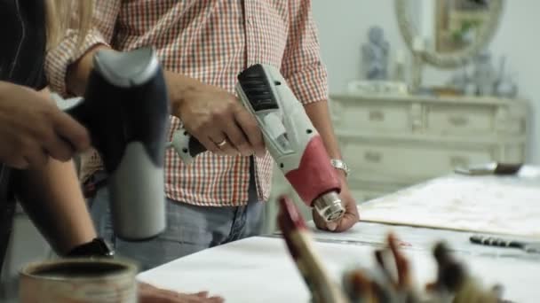 Masters in the art studio process the tree with a construction hair dryer, achieve the aging effect — Stock Video