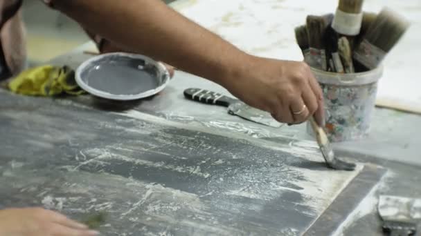 Meesters in de kunststudio verwerken het hout met verf en putty, bereiken het effect van de veroudering — Stockvideo