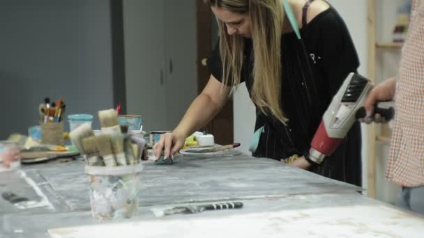 Meesters in de kunststudio verwerken het hout met verf en putty, bereiken het effect van de veroudering — Stockvideo