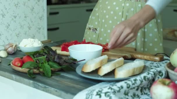Close-up shot of a womans hand is prepared from bread cheese and vegetables for an Italian bruschetta. — Stock Video