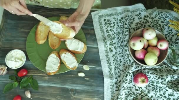 Nahaufnahme einer Frauenhand wird aus Brotkäse und Gemüse für eine italienische Bruschetta zubereitet. — Stockvideo