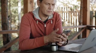 Olgun adam çalışıyor onun laptop üzerinde açık havada doğa onun meslek sırasında büyük tahta masada otururken kontrol e-posta için kendi dizüstü kullanarak forester yaşında.