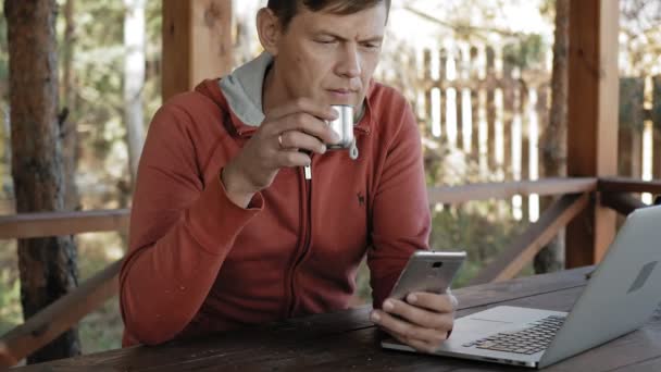 Mogen man arbetar på hans laptop utomhus i naturen under hans kall åldern forester med sin laptop för e-post kontroll medan du sitter på stort träbord — Stockvideo