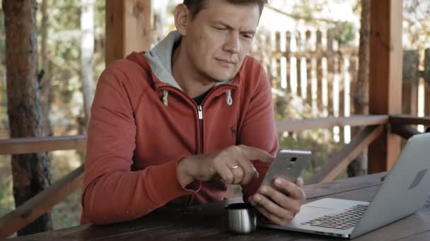 Ein älterer Mann arbeitet während seiner Berufstätigkeit als Förster mit seinem Laptop in der Natur und checkt E-Mails, während er an einem riesigen Holztisch sitzt. — Stockvideo