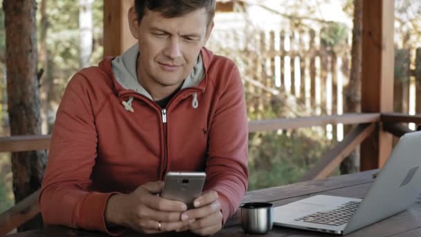 Ein älterer Mann arbeitet während seiner Berufstätigkeit als Förster mit seinem Laptop in der Natur und checkt E-Mails, während er an einem riesigen Holztisch sitzt. — Stockvideo