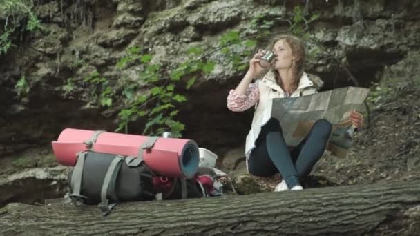 Caminantes mujer está estudiando un mapa en papel de la ruta en el bosque — Vídeos de Stock