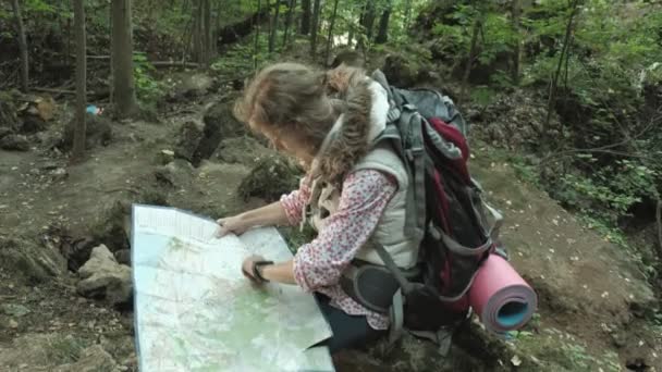 Женщина-туристка изучает бумажную карту маршрута в лесу — стоковое видео