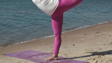Sahilde bazı yoga yaparken eski emekli kadın