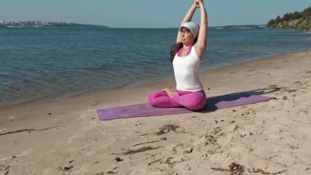 Emerytowany kobieta robi niektóre jogi na plaży — Wideo stockowe