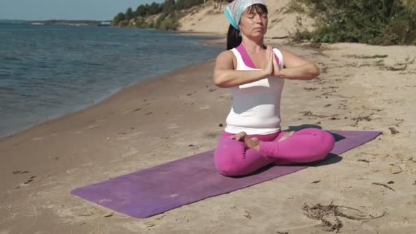 Emerytowany kobieta robi niektóre jogi na plaży — Wideo stockowe