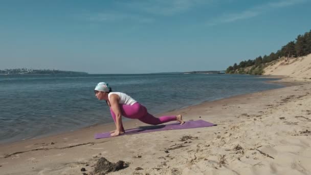 Sahilde bazı yoga yaparken eski emekli kadın — Stok video