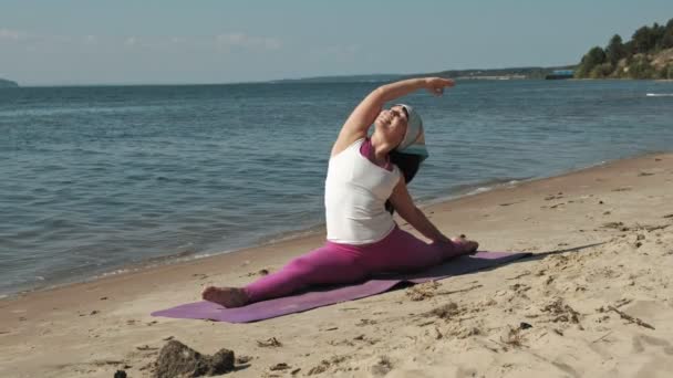 Vecchia donna in pensione facendo un po 'di yoga sulla spiaggia — Video Stock
