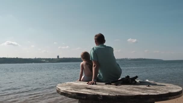 Vater und kleine Tochter sitzen auf einer Holztreppe am Ufer des Flusses — Stockvideo