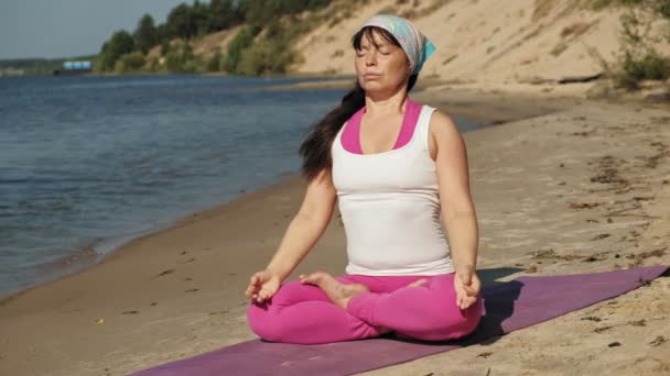 Стара жінка на пенсії робить йогу на пляжі супер повільний рух — стокове відео