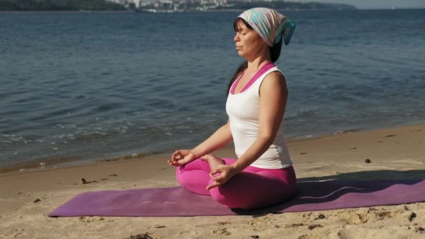 Emerytowany kobieta robi niektóre jogi na plaży super slow motion — Wideo stockowe