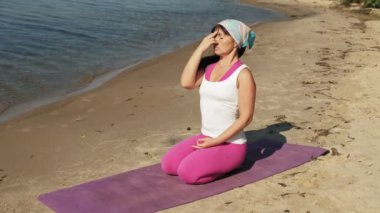 Yaşlı kadın plaj süper ağır çekim üzerinde bazı yoga yaparken emekli