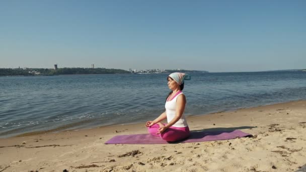 Gammal pensionerad kvinna göra några yoga på stranden super slow motion — Stockvideo