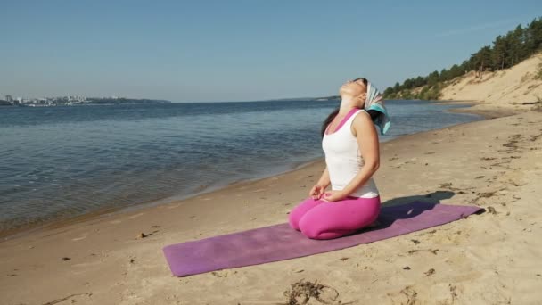 Oude gepensioneerde vrouw doet wat yoga op het strand super slow motion — Stockvideo