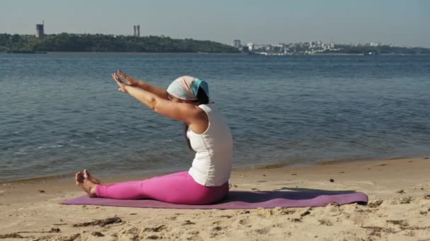 Emerytowany kobieta robi niektóre jogi na plaży super slow motion — Wideo stockowe