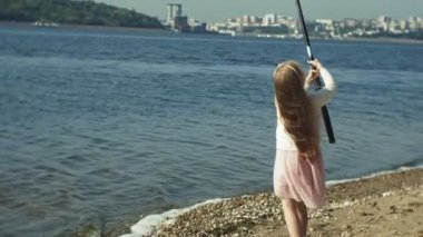 Sevimli küçük kız Nehri yakınında bir balıkçı teknesinde bir olta ile oynuyor