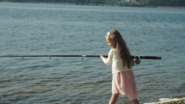 Carina bambina sta giocando con una canna da pesca su una barca da pesca vicino al fiume — Video Stock