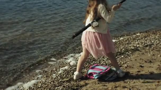 Menina bonito está brincando com uma vara de pesca em um barco de pesca perto do rio — Vídeo de Stock