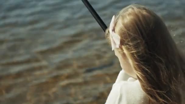 Carina bambina sta giocando con una canna da pesca su una barca da pesca vicino al fiume — Video Stock