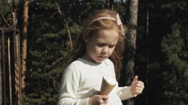 Sevimli bir kız parkta oturan ve dondurma yemek