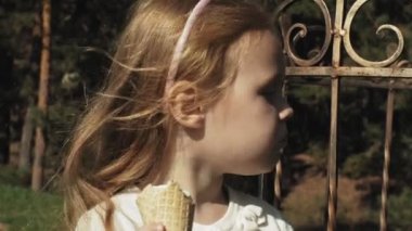 Sevimli bir kız parkta oturan ve dondurma yemek