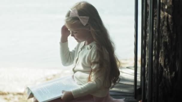 Солодка дівчина сидить у лісі і читає книгу — стокове відео