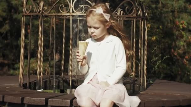 Roztomilá dívka sedí v parku a jíst zmrzlinu — Stock video
