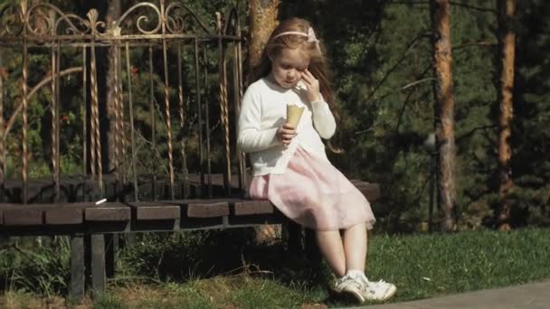 Een schattig meisje is zit in het park en het eten van ijs — Stockvideo