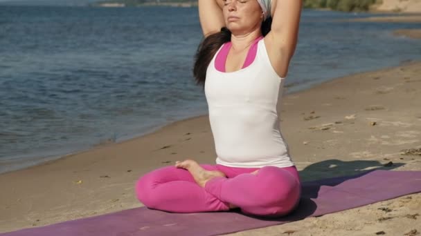 Old retired woman doing some yoga on the beach super slow motion — Stock Video
