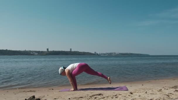 Gammal pensionerad kvinna göra några yoga på stranden — Stockvideo