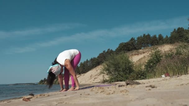 Oude gepensioneerde vrouw doet wat yoga op het strand — Stockvideo