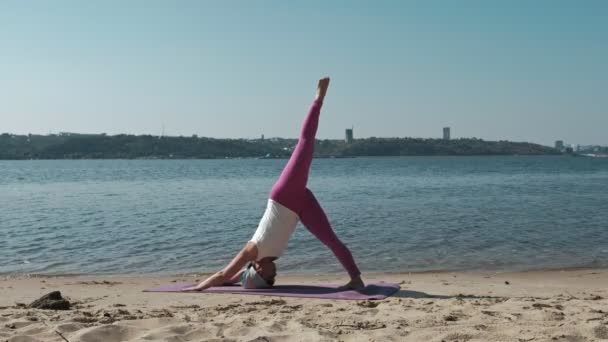 Emerytowany kobieta robi niektóre jogi na plaży — Wideo stockowe