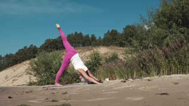 Стара жінка на пенсії робить йогу на пляжі — стокове відео