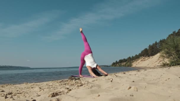 Oude gepensioneerde vrouw doet wat yoga op het strand — Stockvideo
