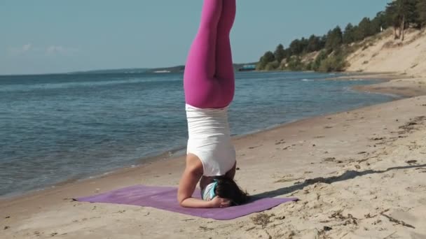 Oude gepensioneerde vrouw doet wat yoga op het strand — Stockvideo