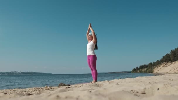 Vecchia donna in pensione facendo un po 'di yoga sulla spiaggia — Video Stock