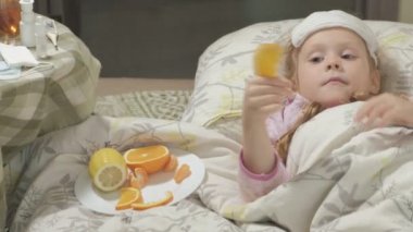 Hasta kız ateşle. Ateşi olan bir çocuğun yatakta yatıyor ve meyve yiyor.