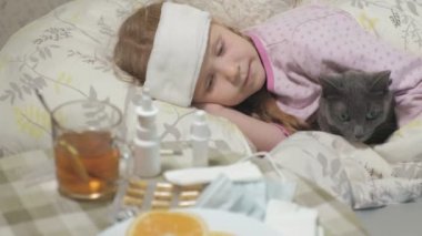 Hasta kız bir sıcaklık. Ateş bir çocukla bir kedi ile yatakta yatıyor.